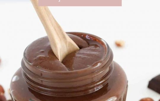 A wooden spoon in a glass jar filled with homemade Nutella.
